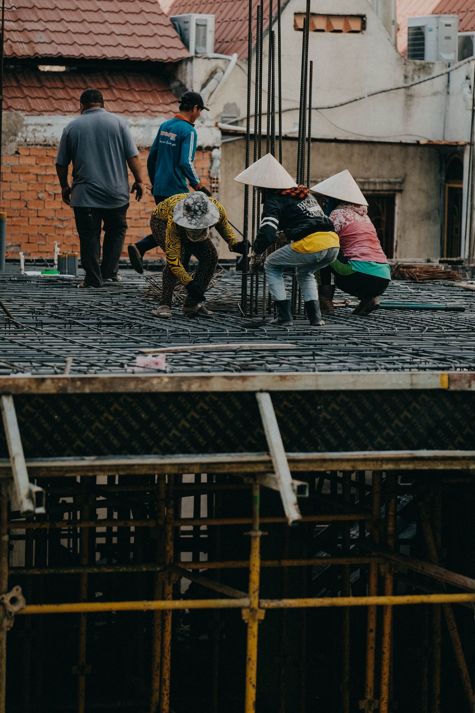 Workers in safety gear on a rooftop construction site in an urban area, showcasing teamwork and industrial activity.