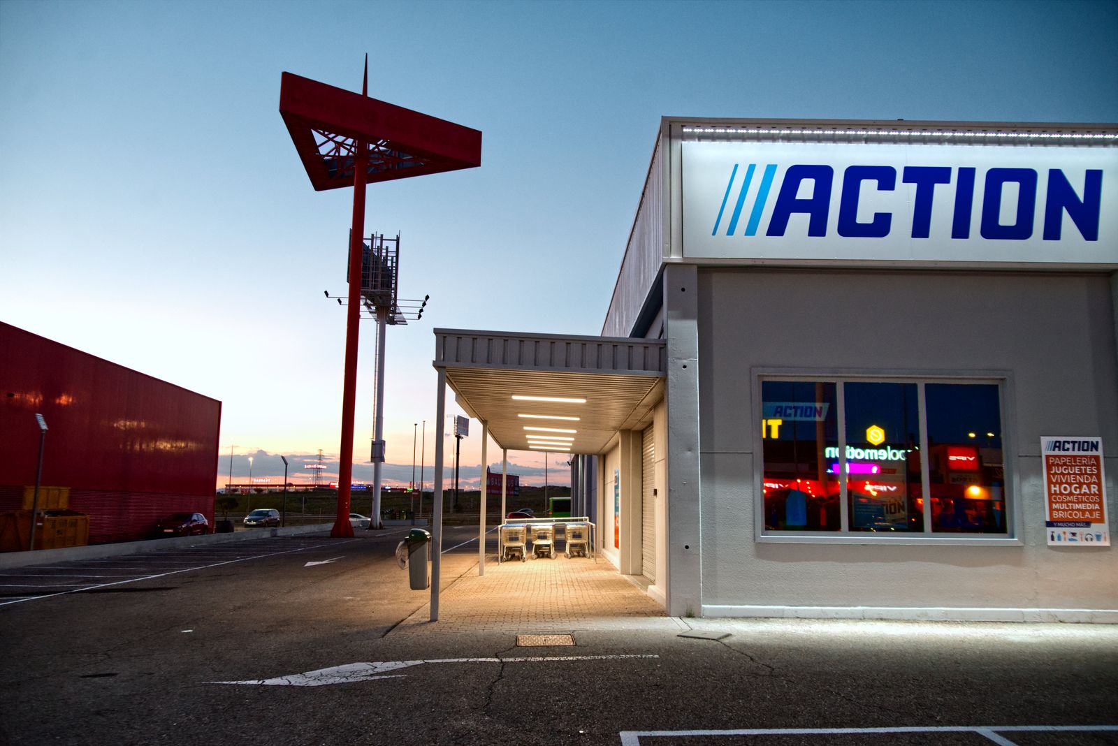 View of a commercial building with illuminated signage and empty parking during sunset.