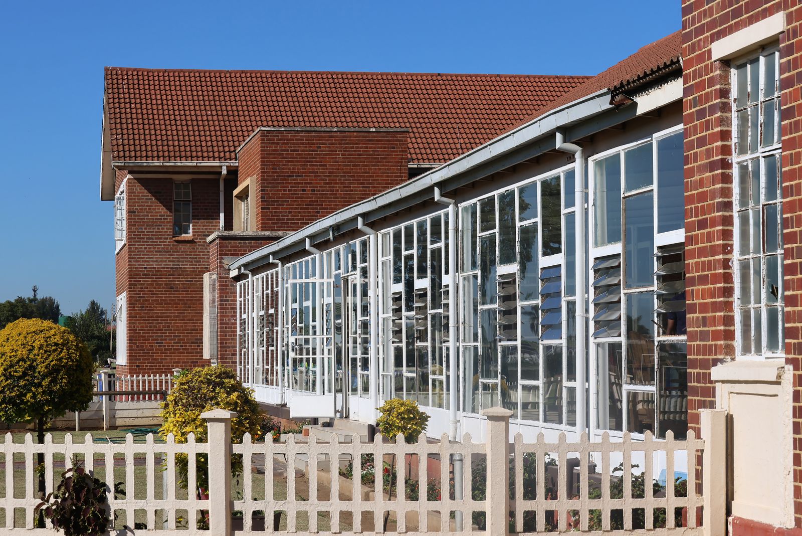 Exterior view of a modern brick building with extensive glass windows and red roof.