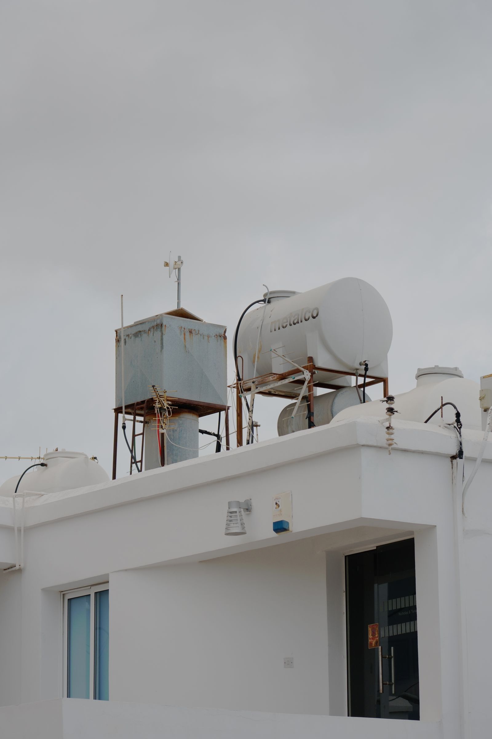 An industrial rooftop with water tanks under a cloudy sky, showcasing urban infrastructure.